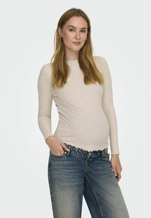 Lange mouwen, lichtbeige ribstof top met een ronde halslijn en een gegolfde zoom, gecombineerd met high-waisted, vervaagde spijkerbroeken.