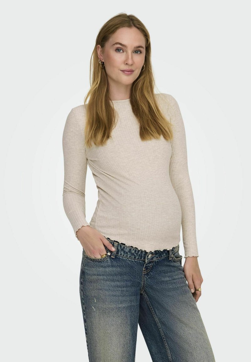 Lange mouwen, lichtbeige ribstof top met een ronde halslijn en een gegolfde zoom, gecombineerd met high-waisted, vervaagde spijkerbroeken.