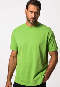 T-shirt verde brillante a maniche corte in cotone. Collo rotondo, vestibilità rilassata, texture liscia e dettagli di cucitura visibili vicino alle maniche e all'orlo.