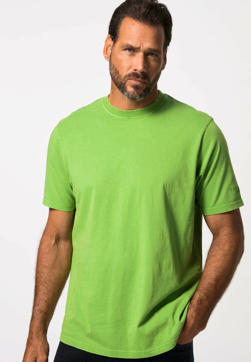 T-shirt verde brillante a maniche corte in cotone. Collo rotondo, vestibilità rilassata, texture liscia e dettagli di cucitura visibili vicino alle maniche e all'orlo.