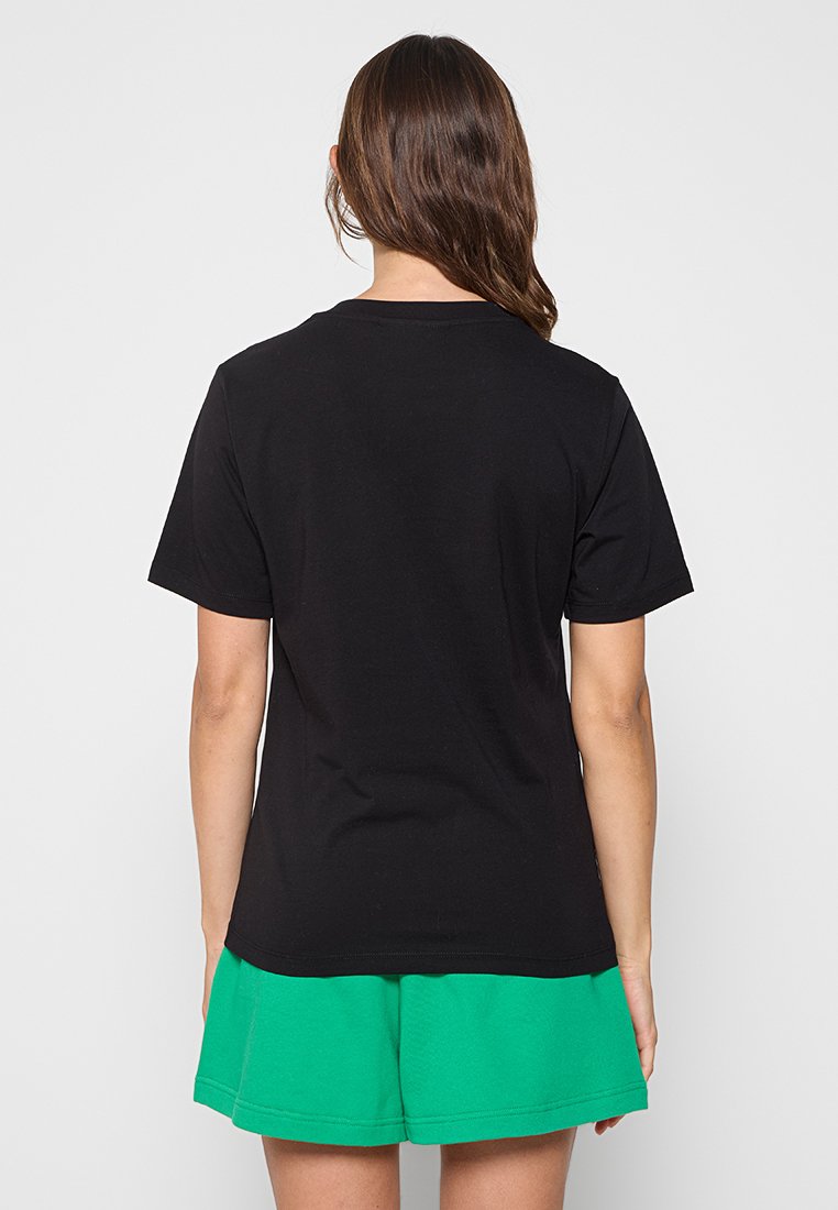 Czarny bawełniany T-shirt z krótkim rękawem, okrągłym dekoltem i prostym dołem, w zestawie z zielonymi szortami o teksturowanej fakturze.