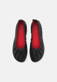 Bailarinas de cuero negro con punta redonda, detalles fruncidos en la parte superior y una plantilla roja con un logotipo en relieve.