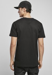 Camiseta de algodón negra con mangas cortas, cuello redondo y una textura suave. Presenta un diseño en la parte posterior liso y sin adornos.