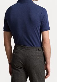 Námořnická polo košile z prodyšného materiálu, s krátkým rukávem a vroubkovaným límečkem. Pár šedých kalhot s texturovaným povrchem a knoflíkovými zadními kapsami.