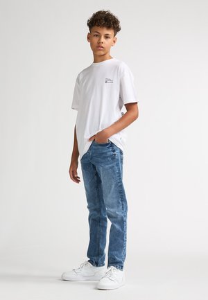 White cotton t-shirt and light blue denim jeans. T-shirt features a small printed logo; jeans have a classic straight fit. White sneakers.