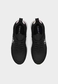 Μαύρα αθλητικά παπούτσια Calvin Klein με λευκό λογότυπο στα πλευρά, σχεδιασμό με κορδόνια και λευκές λεπτομέρειες στη φτέρνα και τη σόλα, από άνω όψη.