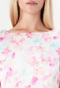 Ύφασμα με ανθισμένα σχέδια που περιλαμβάνει αποχρώσεις του ροζ και του ανοιχτού μπλε, με λεία υφή και πλατιά λαιμόκοψη σε σχήμα βάρκας.