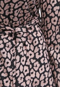 Leopard print fabric in black and soft pink, featuring a belt detail tied at the waist. Smooth texture with an elegant drape.