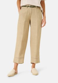 Beiga linnebyxor med lös passform, med en vikta fåll och subtil lila sömnad. Bärs med ljusa slip-on skor.