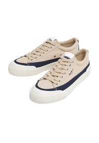 Sneakers in tela beige con accenti blu navy, suole in gomma, punta tonda e lacci piatti. Presentano dettagli cuciti e un logo sul lato.