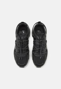 Czarne buty sportowe z wyściełanym kołnierzem, elastycznymi sznurowadłami typu bungee, chropowatą skórzaną cholewką oraz białą gumową podeszwą. Po bokach odblaskowe akcenty.