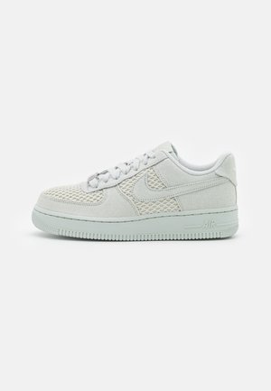 Baskets Nike Air Force 1 gris clair avec panneaux en mesh, lacets et semelle en caoutchouc, vues de côté sur fond blanc.