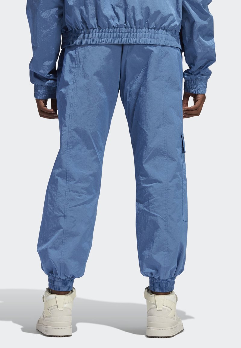 Lichtblauwe, gestructureerde trainingsbroek met elastische boorden en een cargozak. Gecombineerd met witte sneakers. Achteraanzicht getoond.