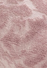 Tissu texturé en rose doux avec une texture pelucheuse, présentant un motif subtil de nuances variées, ajoutant de la profondeur à la surface.
