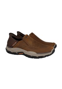 Zapatos de cuero marrón tipo slip-on con tacón texturizado marrón oscuro, suela beige y tracción de goma negra. Se puede ver la marca Goodyear.