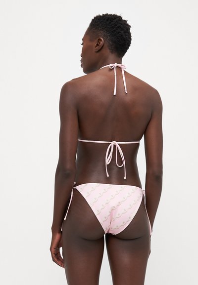 Ροζ μπικίνι με κορδόνια στον λαιμό και κάτω μέρος με ρυθμιζόμενα κορδόνια στο πλάι, διακοσμημένο με ένα διακριτικό κυματιστό σχέδιο σε όλη την επιφάνεια.
