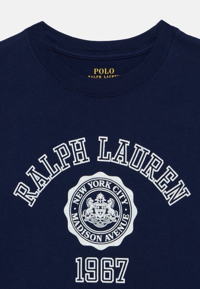 Μπλε ναυτικού χρώματος πουκάμισο Ralph Lauren με κυκλικό έμβλημα Madison Avenue της Νέας Υόρκης και λευκό κείμενο που γράφει «"Ralph Lauren 1967"» στο μπροστινό μέρος.