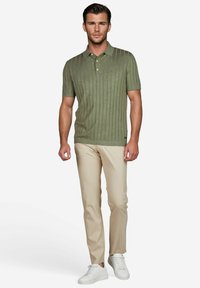 Polo-shirt côtelé vert olive à manches courtes, associé à un pantalon beige clair et des baskets blanches. Design simple et décontracté avec un col.