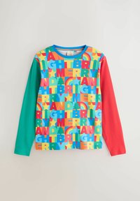 Krāsaina garroku krekls ar ziliem, zaļiem un sarkaniem piedurknēm. Priekšpusē redzams raksts ar lieliem, treknas drukas burtiem un dažādu krāsu formām.