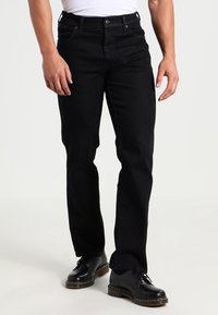 Black denim jeans with a straight leg fit, featuring standard pockets, a zipper fly, and a classic five-pocket design. Worn with black shoes.