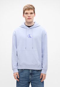 Svetlofialová mikina vyrobená z mäkkého materiálu, s prednou vreckom, kapucňou na šnúrku a logom Calvin Klein na hrudi.