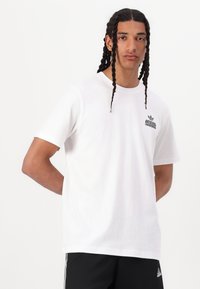 White cotton t-shirt with a round neckline, short sleeves, and a black Adidas logo printed on the left chest. Smooth texture, casual fit.