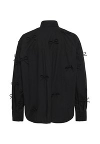 Black shirt with long sleeves, featuring multiple small fabric bows sewn into the chest and sleeves. Made of soft, textured fabric.