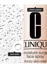 Butelka sprayu do twarzy Clinique Moisture Surge, jasnoróżowa z czarnym logo i napisem, obok kropli wody na białym tle.
