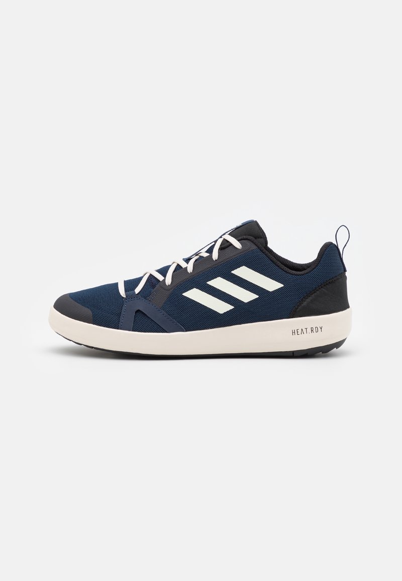 Navy athletic shoe with a textured mesh upper, contrasting white stripes, and a cushioned sole. Features a pull tab and rubber outsole.