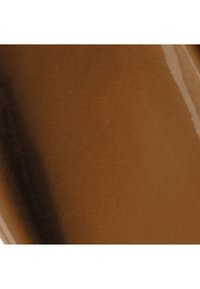 Liquide lisse et brillant de couleur caramel avec un léger reflet de lumière, montrant une texture épaisse et crémeuse.
