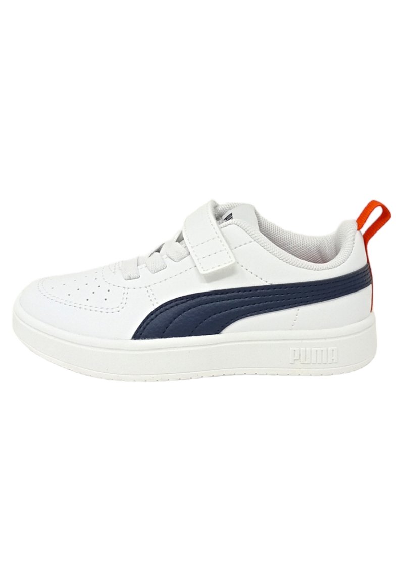 Zapatilla blanca con acentos en azul marino, que cuenta con una parte superior lisa, puntera perforada, correa ajustable y suela texturizada; tirador en el talón rojo.