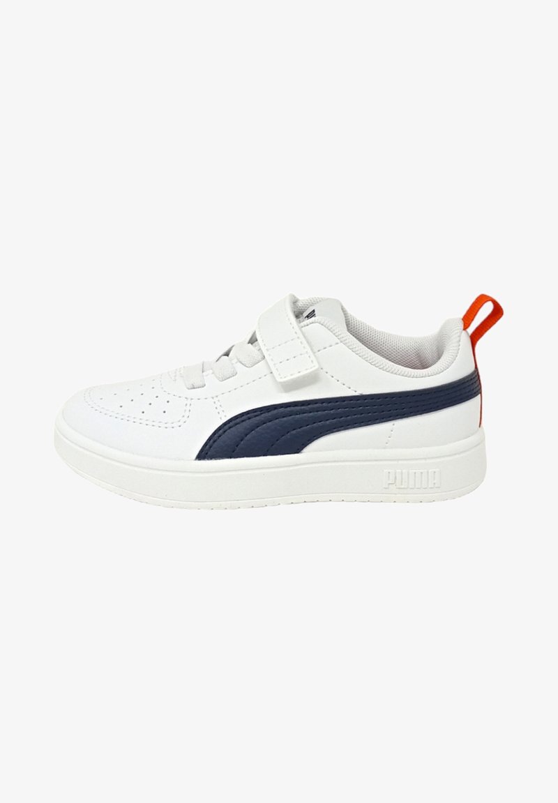 Sneaker bianca con accenti blu navy, dotata di una parte superiore liscia, punta perforata, cinturino regolabile e suola testurizzata; linguetta rossa sul tallone.