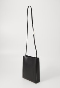 Black leather crossbody bag with a sleek rectangular shape, long adjustable strap, and a front pocket featuring minimal stitching detail.