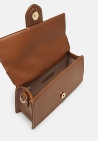 Sac à main rectangulaire en cuir marron avec fermeture pression dorée, rabat ouvert, poche intérieure zippée visible et détail anneau doré sur le côté.