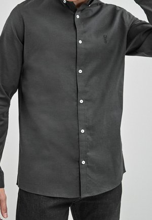 Ciemnoszara koszula na długi rękaw z gładkiej tkaniny, z dyskretnym logo, białymi guzikami i klasycznym kołnierzykiem.