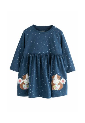 Marineblaues langärmeliges Kleid mit weißen Punkten, mit Raffungen in der Taille, das zwei gestickte Meerschweinchen mit Blumen auf den Taschen zeigt.
