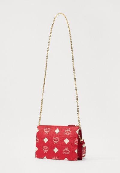 Red crossbody bag with a textured finish, featuring a gold chain strap and diamond pattern with white accents. Zipper closure on top.
