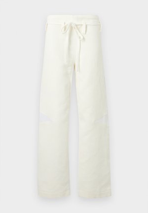 Pantalon droit en velours côtelé blanc cassé avec taille à cordon de serrage et petites découpes en filet aux genoux, présenté sur un fond uni.