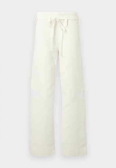 Pantalon droit en velours côtelé blanc cassé avec taille à cordon de serrage et petites découpes en filet aux genoux, présenté sur un fond uni.