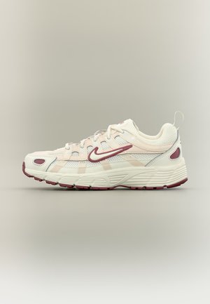 Hvid og lyserød atletiksneaker med bordeauxtapeter og tekstureret sål, sidevisning på ensfarvet lyst baggrund.
