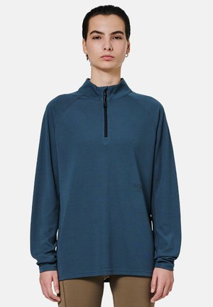 Blauwe textuur lange mouwen pullover met een ritskraag, voorzien van een relaxte pasvorm en subtiele branding op de onderkant aan de linkerzijde.