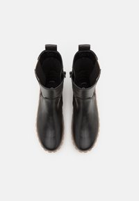 Botas de tobillo de cuero negro con un acabado suave, diseño sin cordones, paneles laterales elásticos y suela de goma. Minimalistas, sin acentos adicionales.
