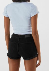 Top azul claro de manga corta con canalé combinado con shorts de mezclilla negros de tiro alto, con dobladillos enrollados y bolsillos traseros.