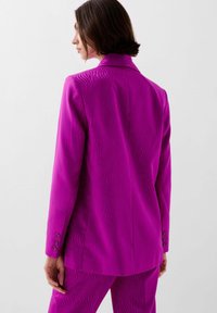 Blazer magenta con un patrón de ola texturizado, cierre de un botón y tres botones en cada manga, disponible en un corte entallado.