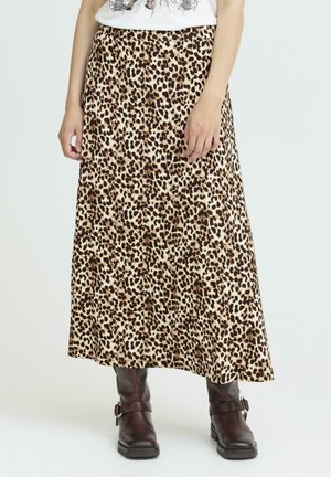Jupe maxi à imprimé léopard en beige et marron, fabriquée en tissu doux avec un design fluide. Associée à des bottes de cheville marron foncé.