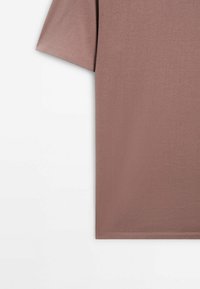T-shirt à manches courtes de couleur mauve atténuée avec coutures visibles à l'ourlet des manches et au bord inférieur sur fond blanc.