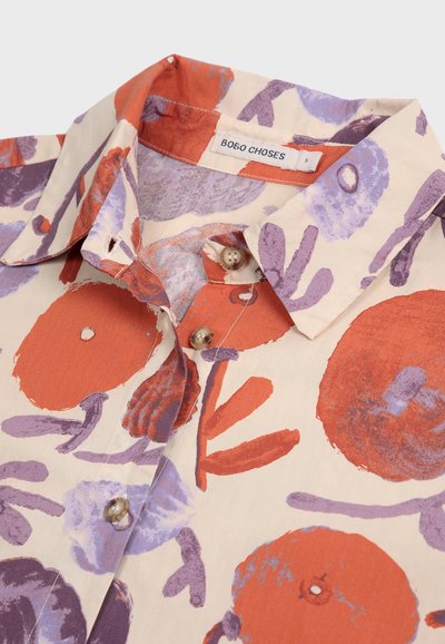 Camicia colletto realizzata in tessuto leggero con uno sfondo crema, caratterizzata da ampi motivi circolari rossi e viola e dettagli con bottoni.