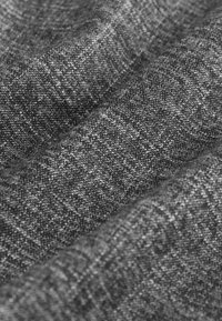 Pilko audinio su struktūra, turinčio skirtingų atspalvių, subtilų raštą ir šiek tiek šiurkštų paviršių, sulankstyto keliomis sluoksniais.