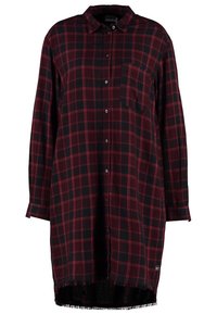 Robe à manches longues avec boutons, motif écossais rouge et noir, poche poitrine, col et ourlet effiloché.