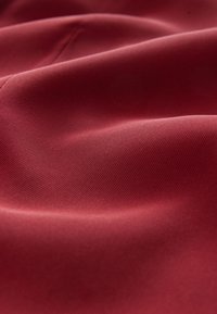 Material textil roșu, neted, cu o textură fină, care prezintă pliuri moi și un luciu subtil. Materialul pare ușor și flexibil.